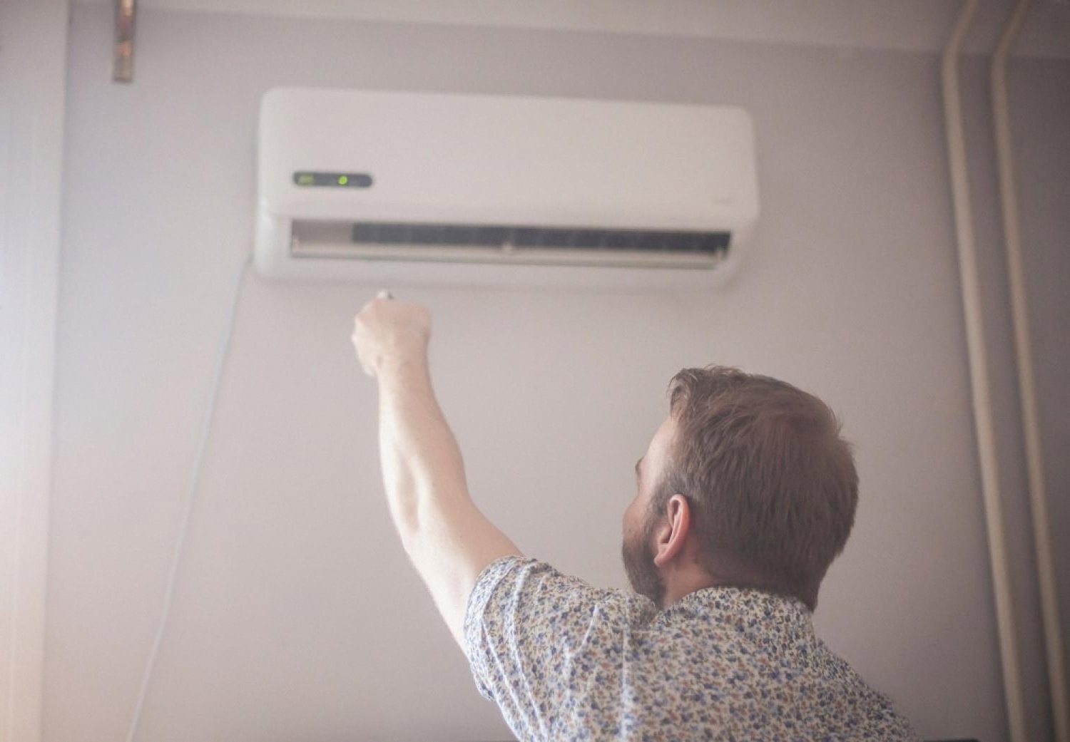 Man switching on a wall-mounted air conditioner inside a Dubai commercial office