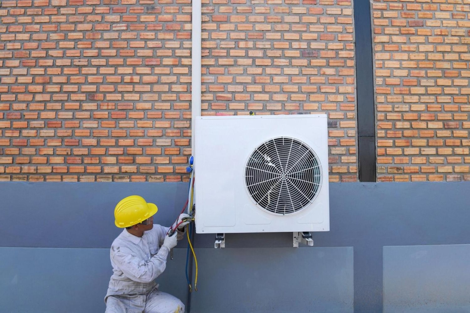 Technician installing an outdoor commercial air conditioning unit on a building in the UAE